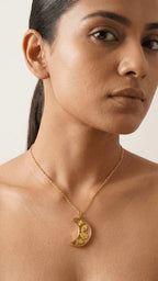 Woman wearing a gold chain with a crescent moon resin pendant featuring yellow dried flowers.