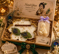 Open gift box containing a lotus-shaped white candle with peacock feather accents, a Krishna idol, and a 'Happy Janmashtami' 