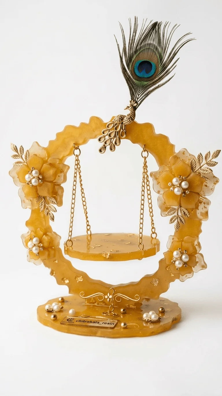 Golden resin Krishna jhula decorated with pearl flowers, gold leaves, and a peacock feather on a white background.
