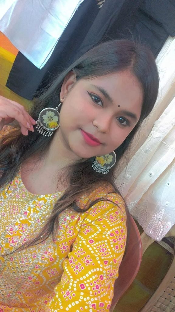 Young woman in a yellow top wearing large silver earrings with yellow resin flowers.