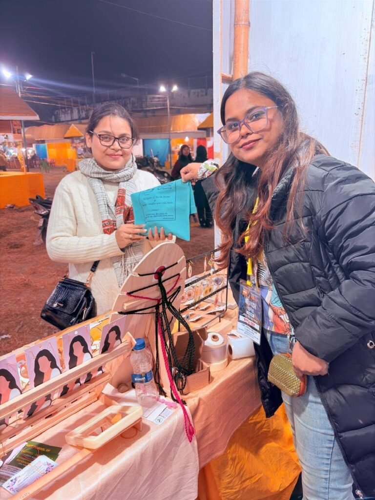 Two smiling women at our Cynosure Titli stall, showcasing handmade resin jewelry and keepsakes at a lively night market event