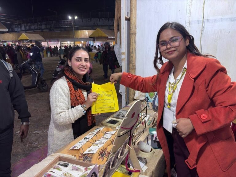 Two women smiling at a bustling night market stall displaying handmade resin jewelry and decor, one holding a yellow bag.