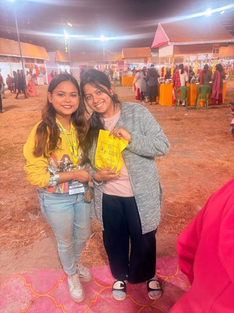 Two women smiling at an outdoor night market, one holding a yellow bag, with illuminated stalls and people in the background.
