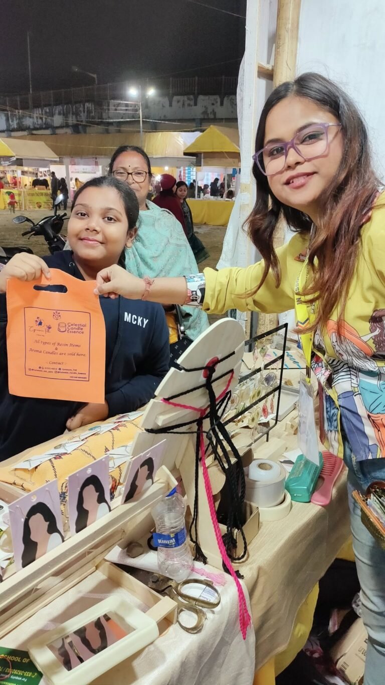 Smiling woman in yellow jacket and girl holding an orange bag at a night market stall displaying handmade resin crafts.