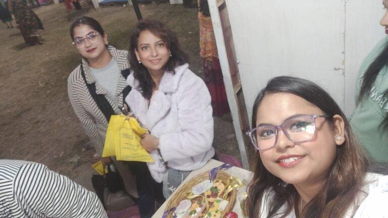 Three women smiling at an event, with one taking a selfie, and handmade resin keepsakes displayed in a basket.