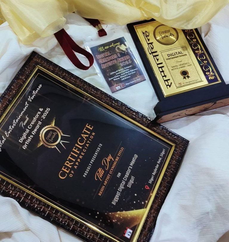 Framed Digital Creators & Artists Award for Cynosure Titli, a gold and black trophy, and event card on light fabric.