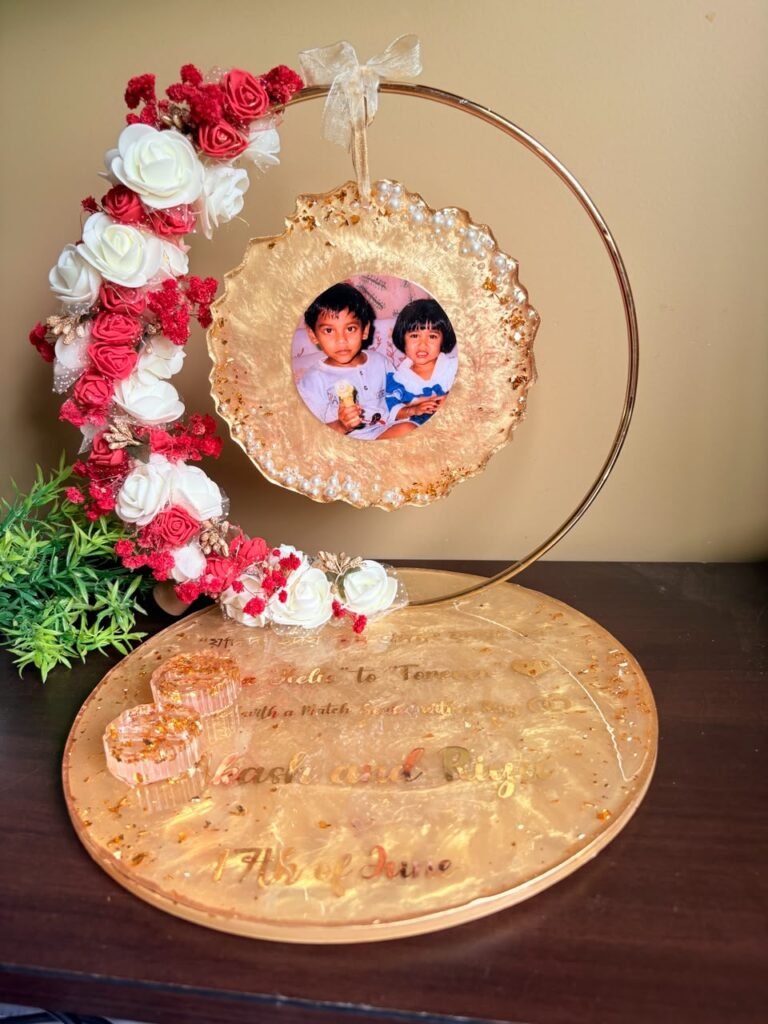 Golden resin photo frame with a picture of two kids, decorated with pearls and red and white flowers, on a personalized base.