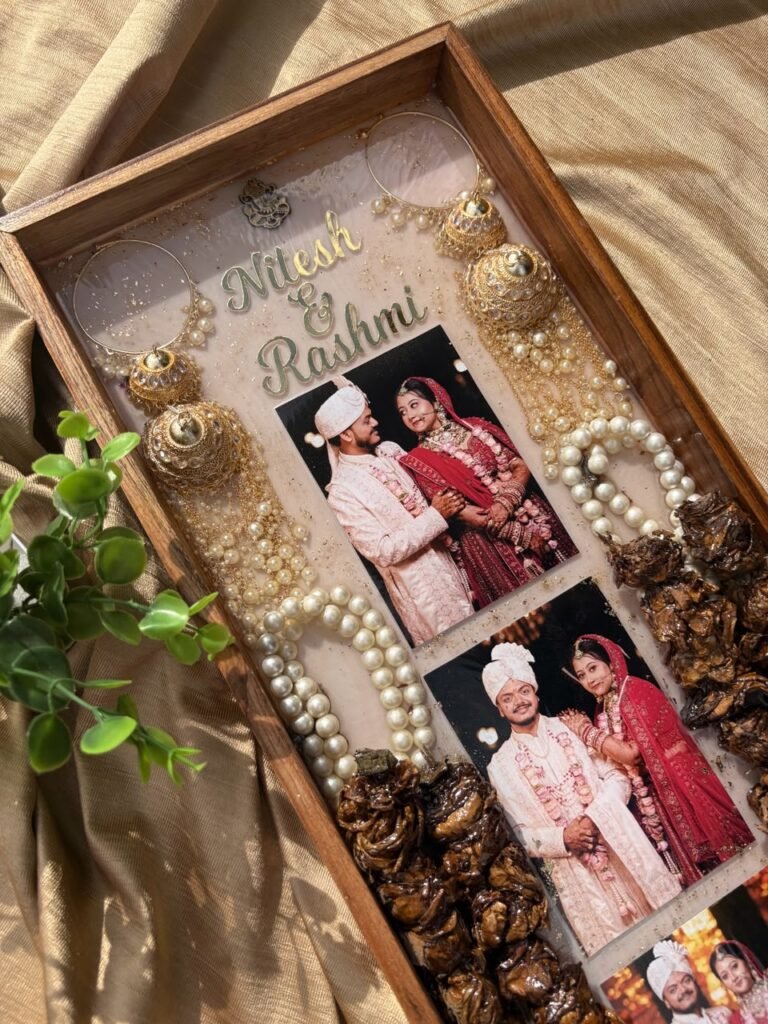 Handcrafted resin wedding keepsake tray with photos of Nitesh & Rashmi, jhumkas, pearls, and preserved elements on golden fab