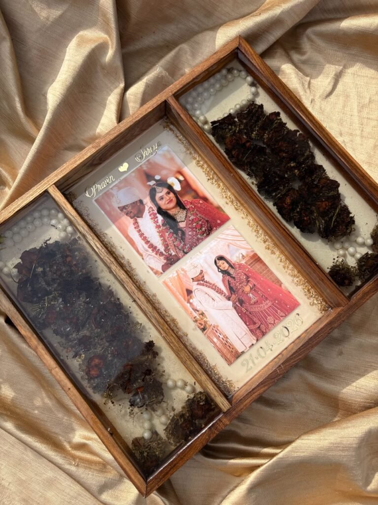 Resin keepsake tray with wedding photos of Pravin & Shweta, dried flowers, and pearls on a golden fabric.
